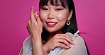 Woman, Asian and face for beauty in studio for skincare makeup happy for cosmetic, pink background or Japan. Female person, smile and portrait or hand touch with confidence, treatment or mockup space