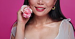 Beauty, fashion and face Asian woman with flower, smile and creative makeup in studio. Happiness, plant and floral aesthetic for girl in Korea with rose lipstick, elegant style and pink background.