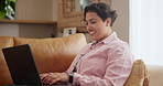 Happy woman, laptop and typing on sofa in relax for email, communication or networking in living room at home. Female person or freelancer smile on computer for online chatting or research at house