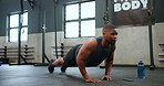 Man, fitness and push ups in workout, exercise or endurance on floor for strength at gym. Active male person, bodybuilder or athlete lifting body weight in muscle gain, chest or biceps at health club