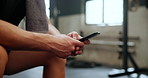 Closeup, gym and man with smartphone, typing and connection with fitness blog and social media. Hands, person or athlete in a wellness center or mobile user with cellphone or digital app with contact