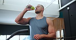 Fitness, health and hydration with man drinking water in gym for break or recovery from workout. Exercise, sports or wellness and confident young bodybuilder with glass bottle for drink at training