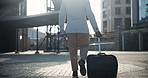 Businessman, suitcase and walking in city for travel, commute or immigration by buildings. Rear view or back of man or employee in business fashion with luggage for opportunity or outdoor work trip