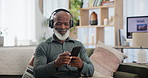 Phone, music and senior black man on sofa in living room of retirement home to relax with headphones. Radio, streaming and weekend with elderly person listening to audio on mobile app in apartment