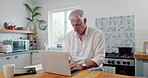 Laptop, research and mature man in kitchen for online with freelance creative project. Technology, reading and senior male freelancer designer typing email on computer at modern apartment or home.