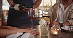 Couple, restaurant and waiter pour wine on date for anniversary meal, valentines day or engagement. Hands, glass and alcohol beverage at table in London cafe for happy celebration, drink or marriage