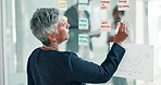Glass wall, business and woman with brainstorming, writing and planning with a project director and creative thinking. Senior person, employee and consultant with schedule and sticky note with ideas