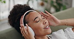 Happy woman, headphones and listening to music, podcast or sound on sofa in living room at home. Calm young female person in relax or enjoying audio streaming, songs or playlist with headset at house