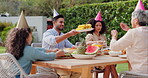 Family, eating and happy with conversation at birthday party for celebration, surprise or hat in garden of home. Couple, parents and kids with drinks for gathering and event in backyard of house