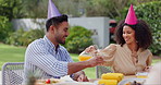 Happy birthday, celebration and couple with orange juice in backyard for brunch, meal or bonding outdoor. Family, lunch and people with food on patio for reunion, event or social gathering on weekend