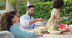 Family, birthday party and lunch in garden for children, parents and celebration at table with giving food. Man, woman and girl kid at event, brunch and eating in backyard with hat to relax at house