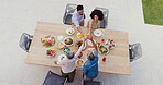 Happy family, above and birthday party in garden with cheers, sharing and eating to bond together by table. Generations, kids or celebrate in green backyard with nutrition or roast meat with drinks