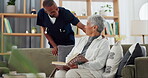 Elderly, woman and nurse on sofa with support, conversation and caregiver in living room of retirement home. Senior, person and man with kindness, happiness and discussion while reading a book