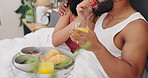 Couple, breakfast in bed and food, happy together with woman feeding man strawberry and orange juice for bonding. Love, trust and nutrition, Valentines day romance and fruit for eating with drink