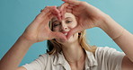 Woman, heart and hands with face and love sign for Valentines day, support and wellness on blue background. Emoji, icon and happy for charity, donation and care in studio, feedback or review for vote