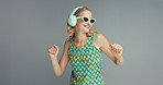 Woman, dancing with headphones and sunglasses, music for fun and energy in studio with happiness on grey background. Entertainment, technology for moving with rhythm and listening to radio in shades