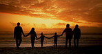 Big family, sunset and walk at beach with back, silhouette and holding hands for love, connection and holiday. People, parents and grandparents with children for link, care and bonding by ocean