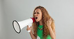 Angry woman, shouting and protest with megaphone for power, rights or equality on a gray studio background. Frustrated female person or activist screaming with fist and bullhorn for announcement