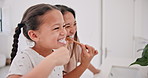 Mother, girl child and brushing teeth in bathroom, health and dental for fresh breathe, bonding and morning routine. People at home, cleaning mouth with toothpaste and toothbrush for oral hygiene