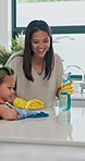 Home, mother and daughter with spray, wipe surface and teaching  with kitchen counter or housekeeping education. Parent, child development or mama with family or cleaning with table, cloth or talking