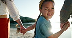 Parents, daughter and happy face for holding hands on beach, sunset and love with bonding on summer holiday. Father, mother and child on sea sand with care, blue sky and relax in nature on vacation