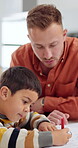Father, son and creative with coloring in home for homework, learning and education with helping or support. Family, man and boy child for drawing in art book with crayons, knowledge and teaching