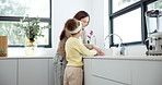 Teaching, kitchen and mother with child to wash hands for hygiene, health or wellness at home. Soap, water and girl kid learning to clean skin with mom to prevent germs, bacteria or dirt at house.