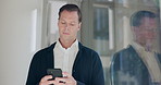 Business man, smartphone and texting in office by window for communication, mobile app and networking. Person, entrepreneur and phone with thinking, idea or decision with contact for deal negotiation