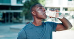 African runner man, drinking water and city for training with break, sweat and breathing for wellness. Person, bottle and hydration for health with exercise, workout and tired with vision for fitness