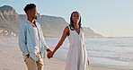 Couple, walking and holding hands on beach for love, romance and talking of date, vacation or valentines day. Young African woman and man by ocean, sea and travel together in Cape Town, South Africa