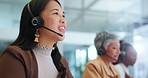 Asian woman, call center and consultant with headphones in agency for customer service or support at office. Female person, team or agents talking or consulting for online advice or help at workplace