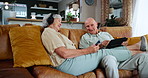 Technology, music and internet with senior couple on sofa in living room of home to relax together. Tablet, phone or headphones for streaming with happy elderly man and woman in retirement apartment