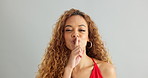 Woman, face and secret hand gesture in studio for announcement silence for gossip, noise or surprise. Female person, portrait and finger on grey background for quiet whisper, hush or mockup space