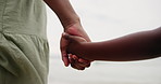 Parent, child and holding hands on beach for support, bonding and holiday with closeup. Back of person or family with kid by the ocean, sea or wind in nature for love, care and safety or security