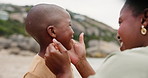 Son, kid and mother with affection on beach for bonding, playing and wipe face with happiness and talking. Black family, mom and child by ocean with love, care or conversation on holiday or vacation