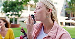 Woman, picnic and eating pastry with friends in outdoor park for sweet dessert snack, delicious or hungry. Female person, donut and relax weekend in London together for connection, happy or holiday