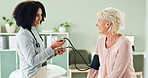 Woman, doctor and patient with blood pressure machine for exam or monitoring heart rate at the clinic. Female person, cardiologist or medical worker measuring pulse in elderly care for hypertension