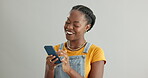 Woman, phone and laughing for chat in studio, happy and funny humor on gray background. Black female person, social media and app for online conversation, contact and comedy on tech and communication