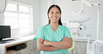 Face, dentist and arms crossed with asian woman in scrubs at hospital for dental care or oral hygiene. Portrait, smile for medical and happy young orthodontist professional at clinic for dentistry