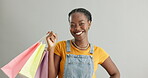 Face, shopping bag or happy black woman with gift in studio isolated on grey background. Customer, portrait or African person with smile, present or product on discount deals or promotional offer 