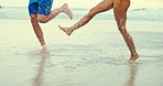 Couple, legs and beach with water splash for fun holiday, weekend or outdoor bonding together. Closeup of man and woman feet running, enjoying or playing on the ocean coast by the sea in nature