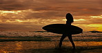 Sunset, silhouette and woman with a surfboard, beach and water with fitness and vacation. Person, girl and surfer with ocean and seaside with clouds and summer with wellness and nature with adventure