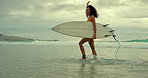 Beach, freedom in summer and woman walking with surfboard on sand by sea or ocean for travel. Smile, surfing and morning with happy young surfer person n coast for sports, training or leisure hobby
