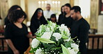 Funeral, death and people at coffin with flowers at memorial service at church for respect, support or comfort. Blur, grief or family with roses, memory and goodbye at casket for spiritual farewell