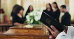 Funeral, hands or priest reading bible at church or memorial service for respect, rip or ceremony. Sad grief, death or closeup of pastor reading holy book for goodbye by coffin for spiritual farewell