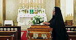 Sad, coffin and mourning with widow at funeral for grief, loss of pain in church for farewell ceremony. Depression, death or goodbye and mature woman at temple with rose flower for memorial service