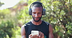 Man, headphones and phone for music, runner and streaming radio for fitness workout in nature. Black male person, cardio and app or website for playlist, audio subscription and training for marathon