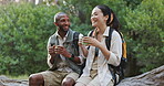 Friends, coffee and relax on hike outdoors, conversation and hot drink for break on trek in woods. People, laughing and tea on holiday or vacation in forest, bonding and talking on travel in nature