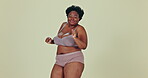 Dancing, body positivity and face of black woman in underwear in a studio for self love celebration. Happy, smile and portrait of young African female model moving with confidence by green background