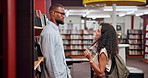 University, talking or couple at school in library for research, college education or knowledge in books. Interracial, conversation and students in campus for learning or studying for scholarship